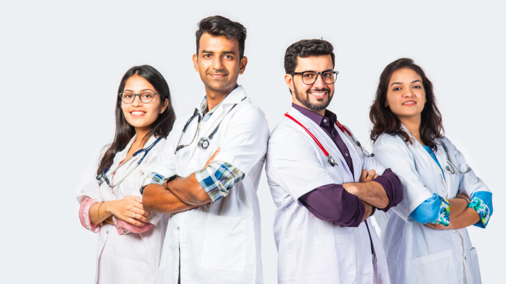 Four medical professionals posing confidently in white coats with stethoscopes.
